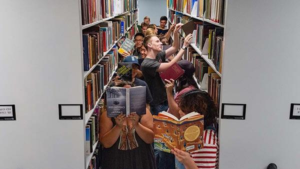 学生们在图书馆的书架上玩得很开心