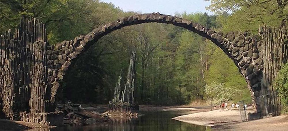 一座参差不齐的拱形石桥及其在水中的倒影，形成了一个诡异的圆圈