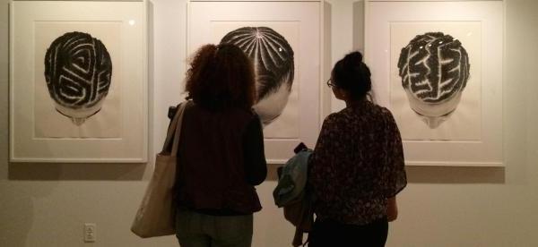 Two people view three images in an art exhibit.